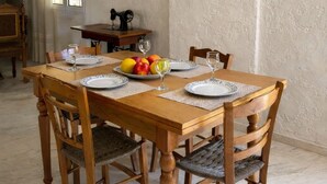 Ein Essbereich mit Holztisch, Stühlen, einer Obstplatte und einem Gemälde an der Wand.