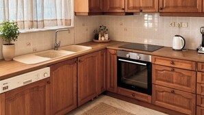 Eine Küche mit Holzausstattung, einem Backofen, einer Spüle und einem Fenster mit Vorhängen.