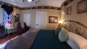 A bedroom with a bed, dresser, mirror, lamp, and two doors.