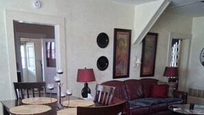 A dining area with a table, chairs, and a lamp. There is a sofa and a coffee table in the living area.