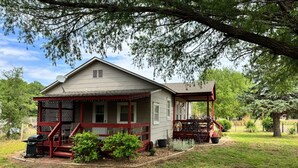A house with a porch, a barbecue grill, and a small garden area.