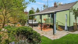Ein Haus mit einer überdachten Terrasse, einem Whirlpool und einer Treppe, die zum Eingang führt.
