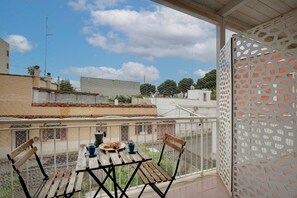 A balcony with a table, chairs, and a view of buildings and trees. - Studio 'Garibaldi54 - Camera del Fico' with Balcony, Wi-Fi and Air Conditioning (Bari)