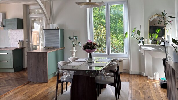 Una cocina moderna con comedor, pisos de madera y un amplio ventanal con vista a follaje.