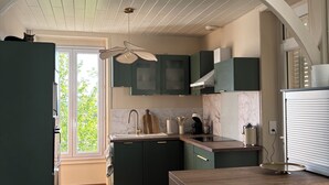 Una cocina moderna con armarios verde oscuro, una encimera de madera y un ventilador de techo.