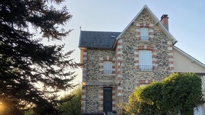 Una casa de piedra con un balcón, una puerta y un pequeño jardín.