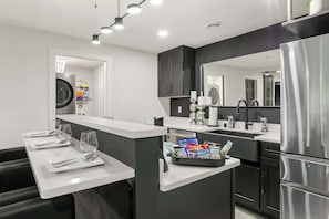 A modern kitchen with a central island, stainless steel appliances, and a large mirror. - Game Room - King Suite - Theatre Room - Fireplace (Sun Prairie)