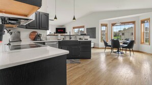 Una cucina moderna con mobili scuri, un'isola centrale e luci a sospensione.