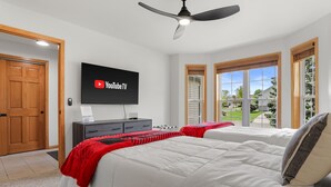 Camera da letto con due letti, una ventola a soffitto, un televisore montato a parete e vista sull'esterno.