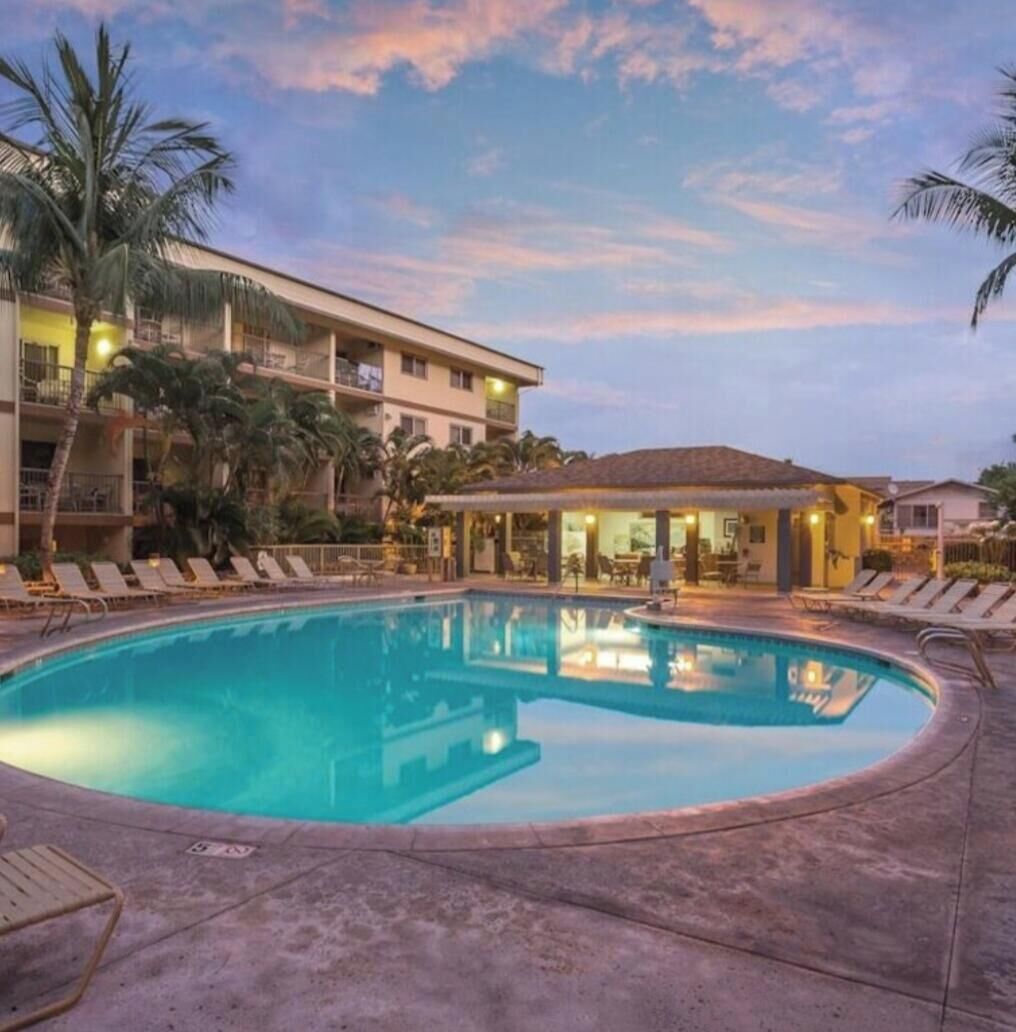 A hotel pool area with lounge chairs and a building with balconies.