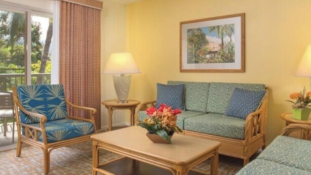 A room with a sofa, a chair, a table, a ceiling fan, a window with curtains, and a framed picture on the wall. - Cozy 1-bedroom fully furnished condo sleeps 4 in serene Kailua-Kona with AC (Kailua-Kona)