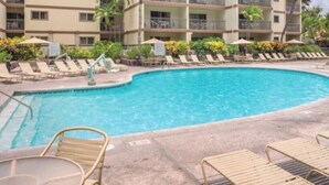 A hotel with a swimming pool, multiple balconies, and lounge chairs. - Cozy 1-bedroom fully furnished condo sleeps 4 in serene Kailua-Kona with AC (Kailua-Kona)