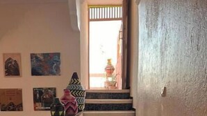 Uma escada com corrimão, que leva a uma porta com vista para o exterior.