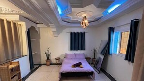 Quarto com cama, luminária no teto, janela e planta em vaso.