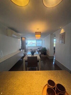 A modern kitchen with a dining area, a large window with a view, and a ceiling light fixture. - Beachfront apartment with a spectacular view of Flexas beach!! (Niterói)