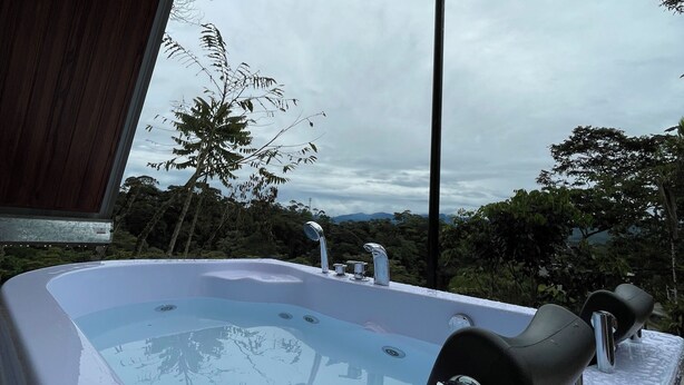 A hot tub with a view of the surrounding landscape. - Refugio de la Niebla Puyo Glamping (Puyo)