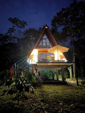 A triangular-roofed building with a balcony, surrounded by greenery.