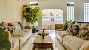 A living room with two sofas, a coffee table, and a large plant. -  Townhouse Oak near Duta Mall Palangka Raya formerly Hotel Nascar Family (Palangkaraya)