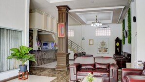 A spacious lobby with a reception desk, a staircase, leather seating, and a chandelier. -  Townhouse Oak near Duta Mall Palangka Raya formerly Hotel Nascar Family (Palangkaraya)
