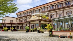 A hotel with a central entrance, multiple balconies, and a covered area with potted plants. -  Townhouse Oak near Duta Mall Palangka Raya formerly Hotel Nascar Family (Palangkaraya)