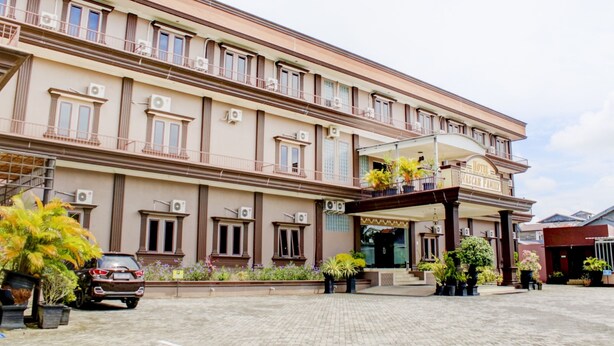 A hotel with a central entrance, multiple balconies, and a parking area with a car. -  Townhouse Oak near Duta Mall Palangka Raya formerly Hotel Nascar Family (Palangkaraya)