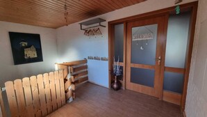 A wooden staircase, a door with frosted glass panels, and a welcome sign. - Large vacation apartment with garden (Lauda-Königshofen)