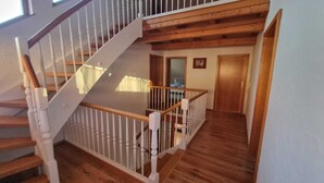 A wooden staircase with white railings leading to a second-floor landing. - Large vacation apartment with garden (Lauda-Königshofen)