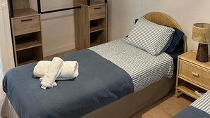 Un dormitorio con cama, mesita de noche, lámpara, armario y lámpara colgante.