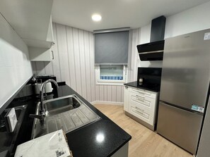 A modern kitchen with a stainless steel refrigerator, a black countertop, a built-in oven, and a window with blinds. - Free Parking & WiFi: Your base in Haro (Haro)