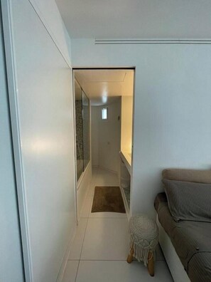 A narrow hallway leading to a bathroom with a shower and a small window. - Moderno apartamento en Ibiza (Ibiza)