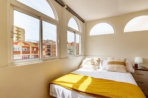Ein Hotelzimmer mit einem Bett, einem Nachttisch und drei Fenstern.