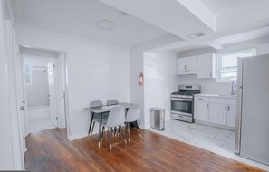 Eine moderne Küche mit weißen Schränken, einem Edelstahl-Kühlschrank und einem Essbereich mit Tisch und Stühlen.