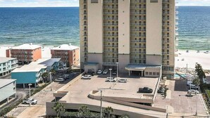Ein Hochhaus-Hotel mit mehreren Etagen, einem Parkplatz und Blick auf den Strand.
