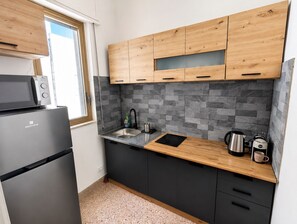 Pieni, käytännöllinen keittiö, jossa on mikroaaltouuni, pesuallas ja kahvinkeitin.