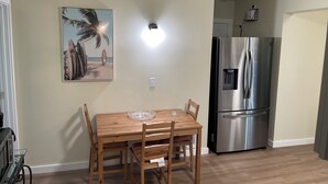 A dining area with a wooden table and chairs, a stainless steel refrigerator, and a wall-mounted light fixture. - Vacation Home at Lake Serene (Lynnwood)