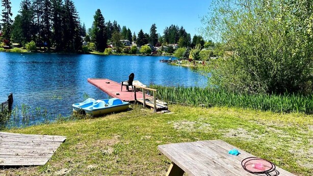 A lakeside picnic area with a dock, boats, and a table with a badminton racket. - Vacation Home at Lake Serene (Lynnwood)