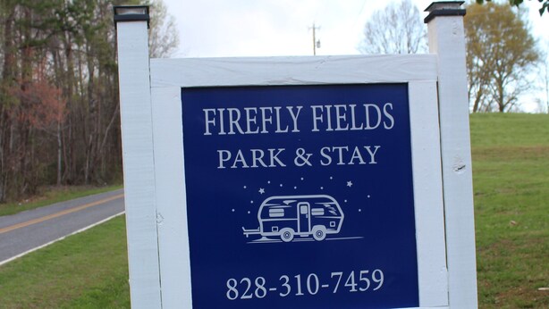 A sign for Firefly Fields Park & Stay with a contact number.