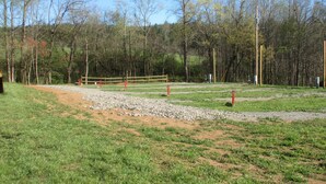 A fenced outdoor area with a gravel path, grass, and trees in the background.