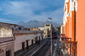 Una calle estrecha flanqueada por edificios, con una montaña al fondo y un cielo despejado.