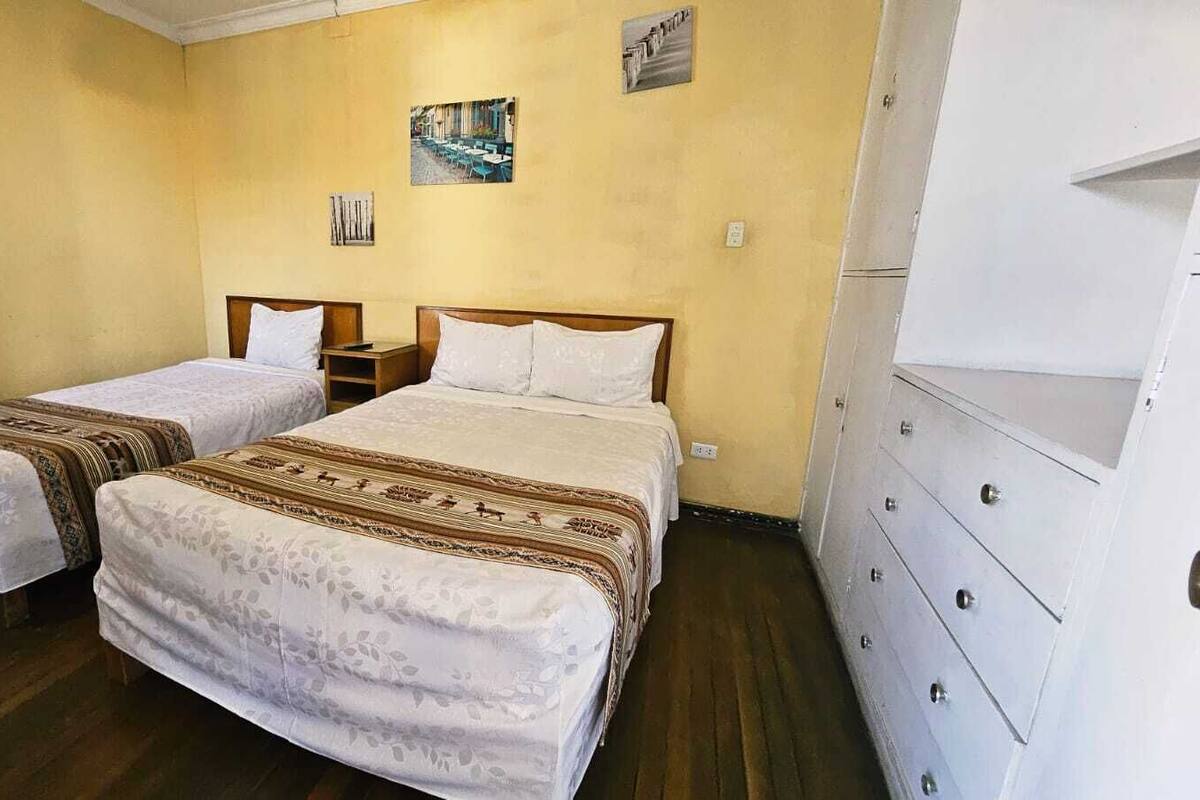 A room with two beds, a dresser, and a wall-mounted shelf.