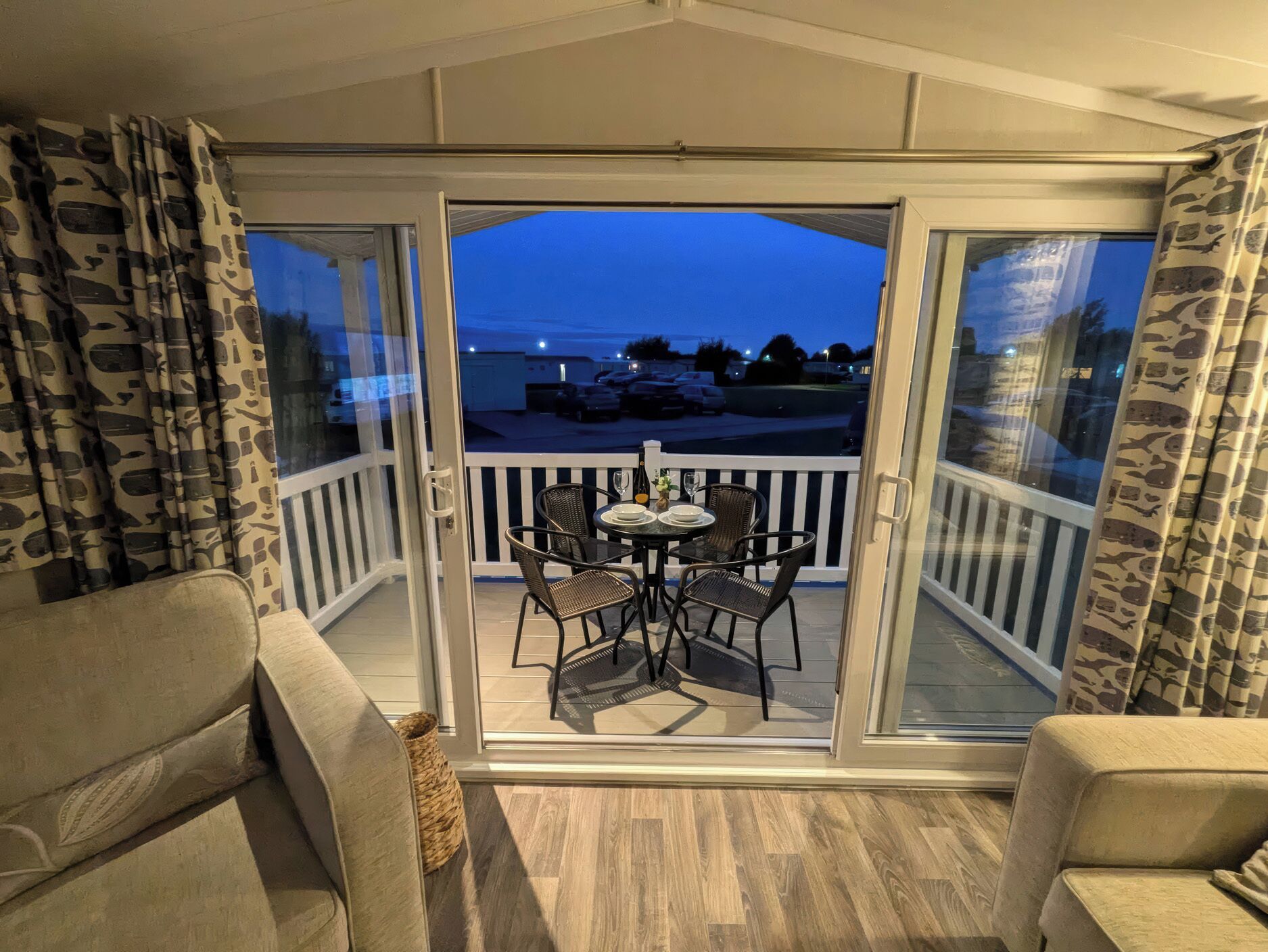 A balcony with a table and chairs, a view of the sea, and a building in the background.