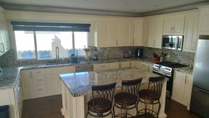 A kitchen with a granite countertop, white cabinetry, a built-in stove, and a large window. - Beautiful 4 bedroom vacation home in Punta Azul (Rosarito)