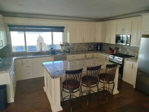 A kitchen with a granite countertop, white cabinetry, a built-in stove, and a large window.