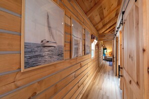 Ein Innenkorridor aus Holz mit einem Poster von Segelbooten, Holzwänden und einer sichtbaren Tür.
