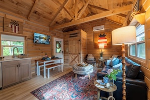 Ein rustikaler Holzblockhaus-Innenraum mit Küche, Essbereich und Wohnzimmer.