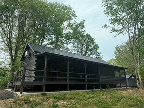 Una cabaña de madera con techo de metal, rodeada de árboles.