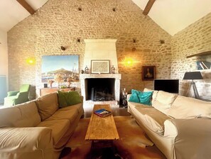 Ein gemütliches Wohnzimmer mit Steinwänden, einem Kamin, zwei Sofas und einem Couchtisch.