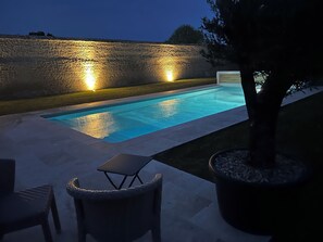 Ein Pool mit einer Steinmauer und einem Baum im Vordergrund.