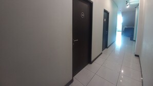 Un passadís amb dues portes, una d'elles amb el número 108, que condueix a una habitació. El terra està emblamat i les parets pintades de color clar.