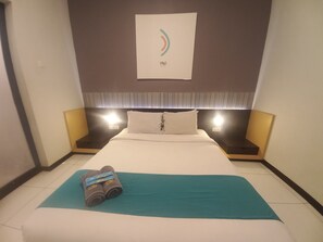 A hotel room with a bed, two bedside tables, a wall-mounted light, and a towel on the floor. - Collection O near Paragon City Mall Sema (Semarang)